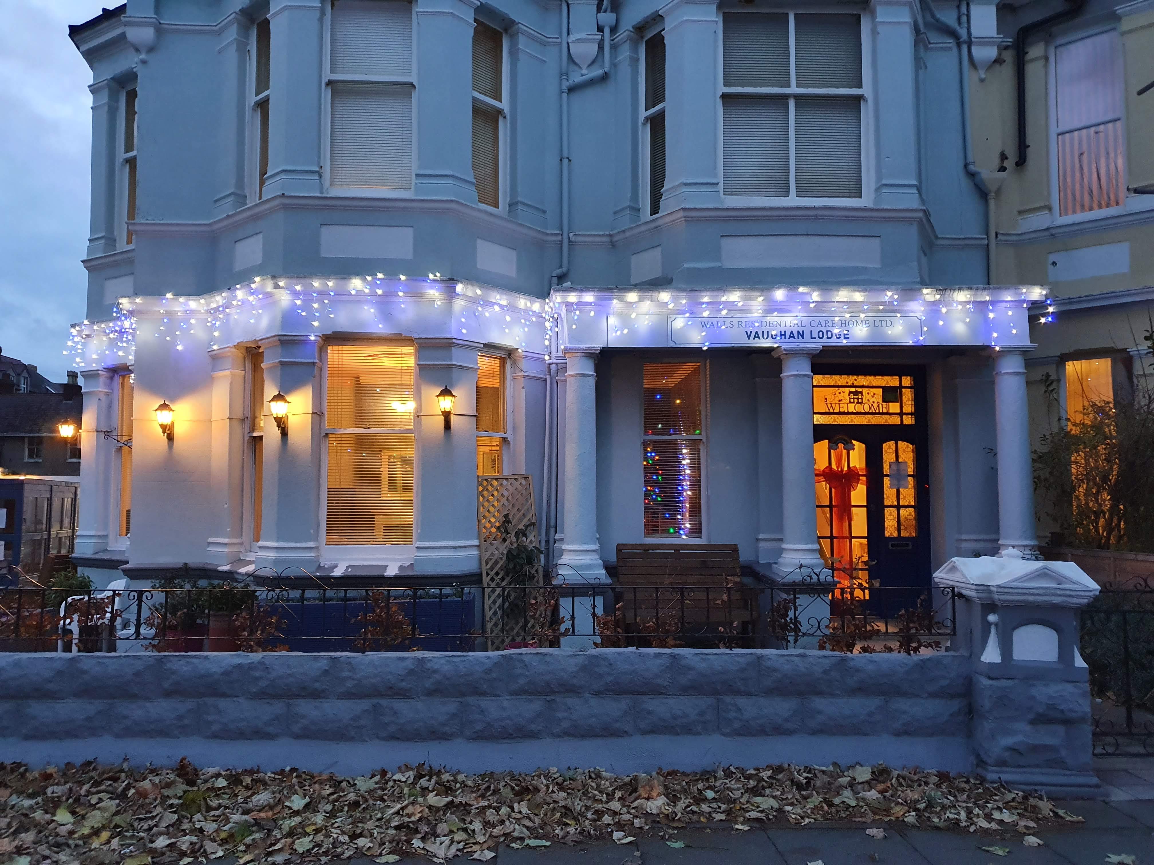 A large, three-story building with antique-style pillars, illuminated by lights on the ground floor, depicting a veterinar...